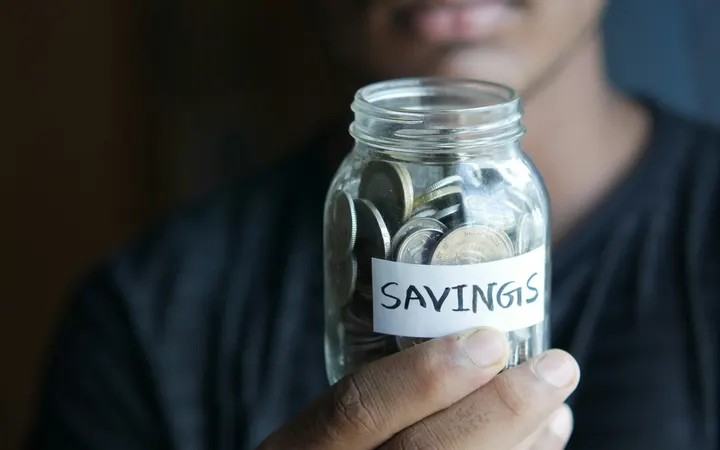 Man holding a glass jar of coins labeled savings