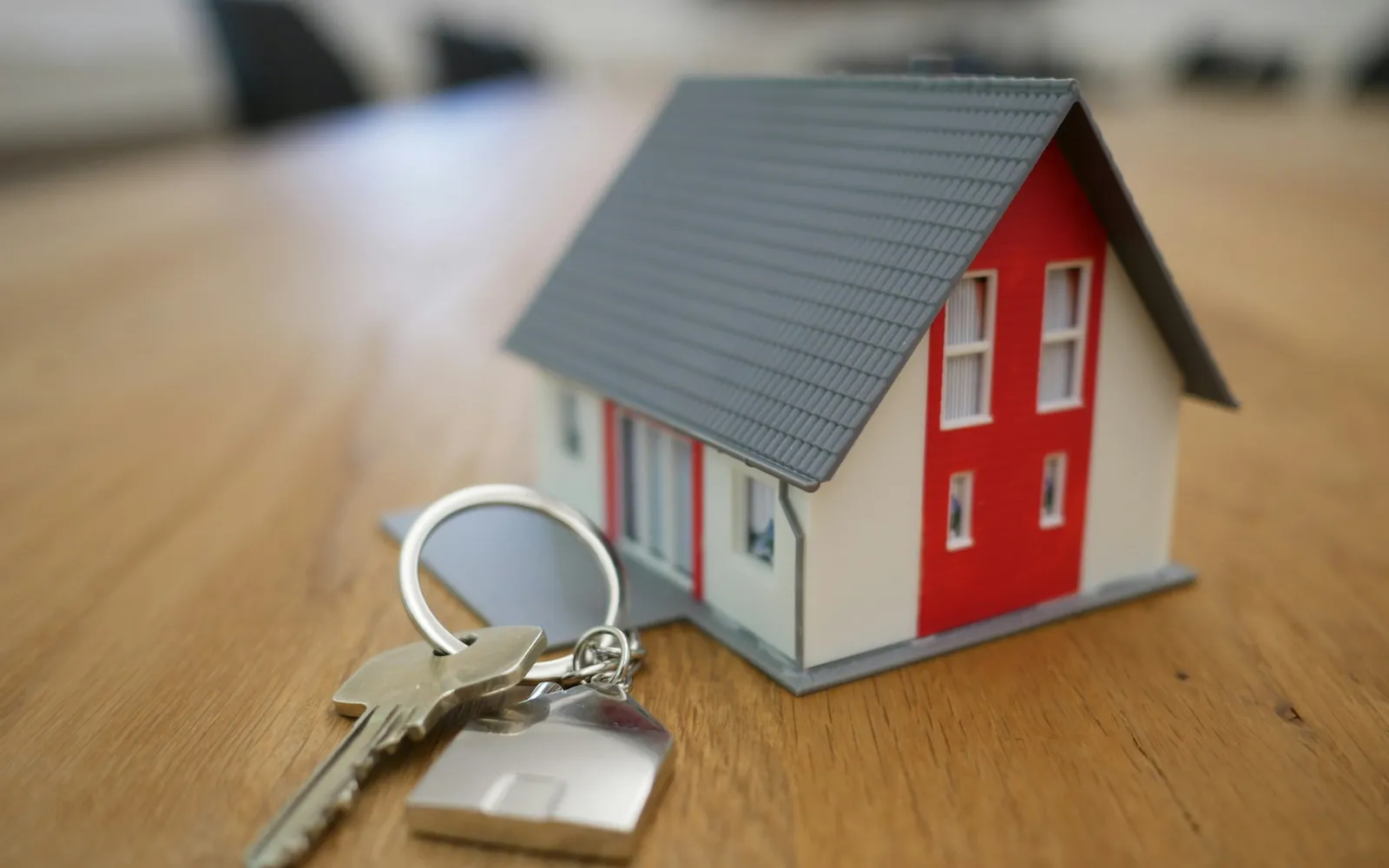 Model house and keys on a wooden table